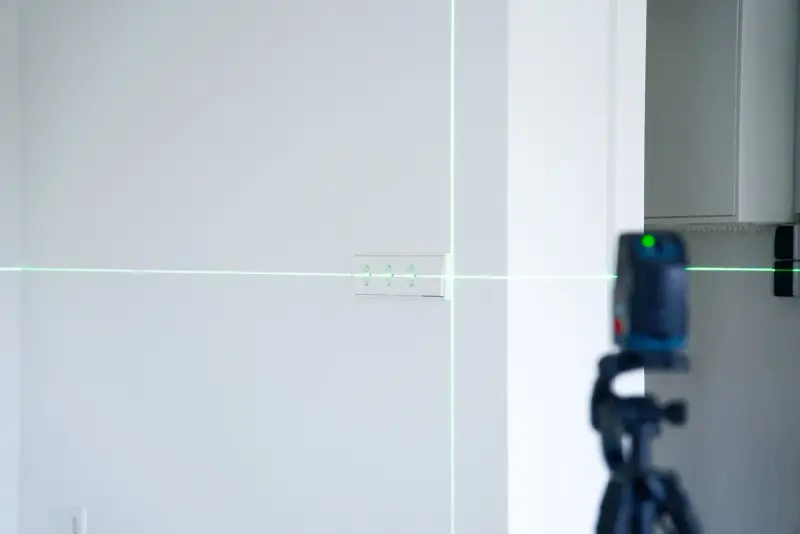 Kreuzlinienlaser richtet die Bohrungen für Steckdosen an der Wand aus
