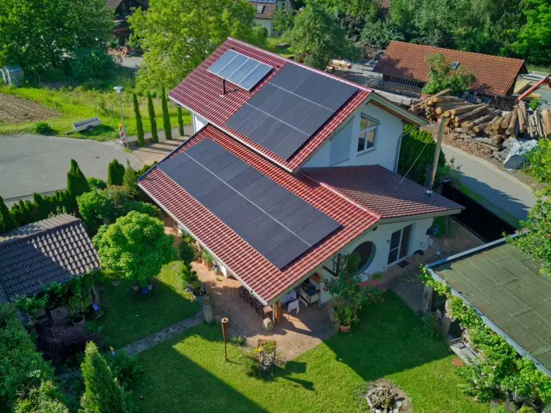 Luftbild eines Hauses mit Solarmodulen im Grünen